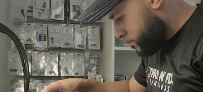 Willy, a Talk N Fix Wireless technician, repairing a Samsung phone at the workbench